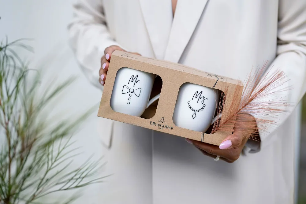A person is holding a gift box containing two Statement cups with the inscription “Mr.” and “Mrs.”.