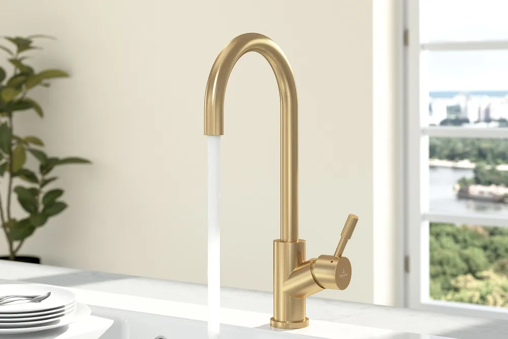 A gold Umbrella tap on a white sink with white plates on the draining board.
