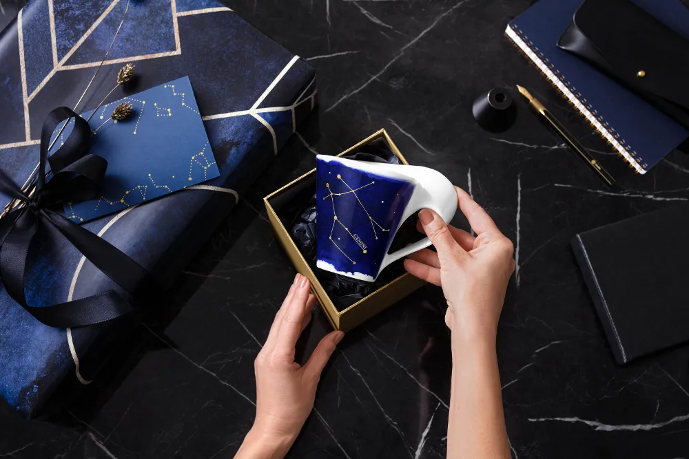 New Wave mug with the "Gemini" zodiac pattern from Villeroy & Boch is gift-wrapped on a dark background.