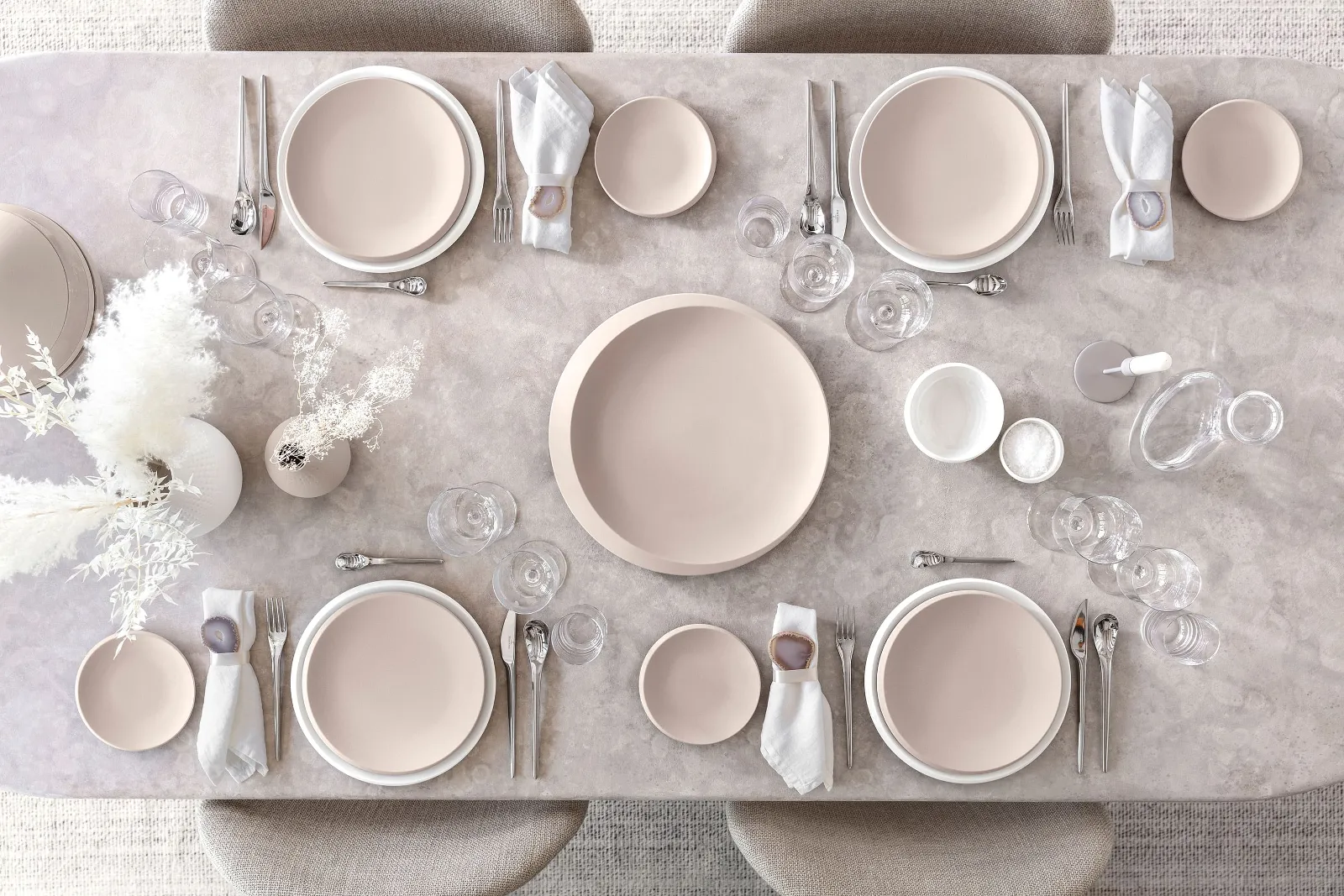 Une table dressée avec des assiettes NewMoon en beige et blanc ainsi que des couverts de table et des verres de Villeroy & Boch.