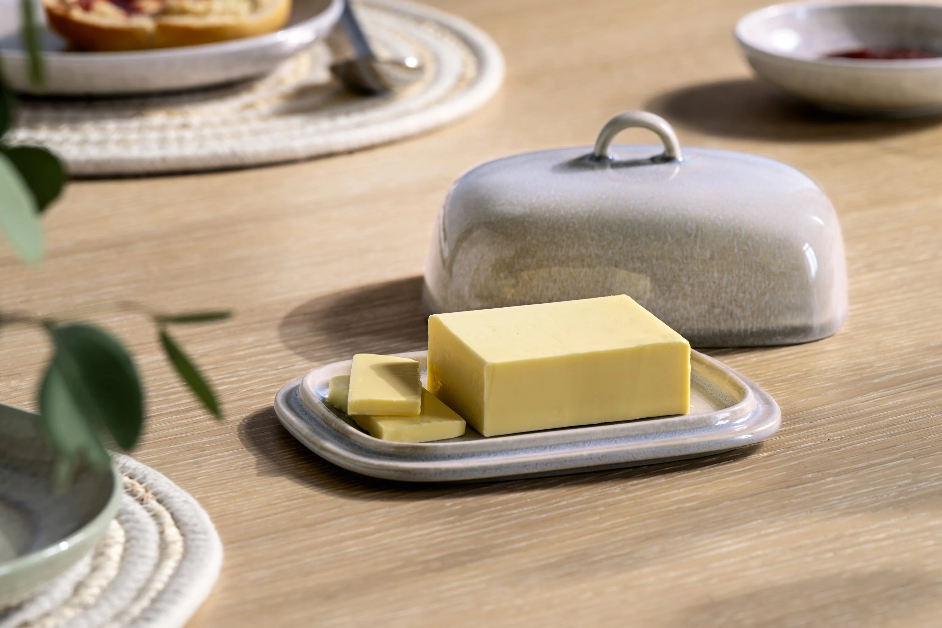 A Perlemor butter dish on wood table A rectangular Perlemor butter dish with a cut piece of butter sits on a wooden table.
