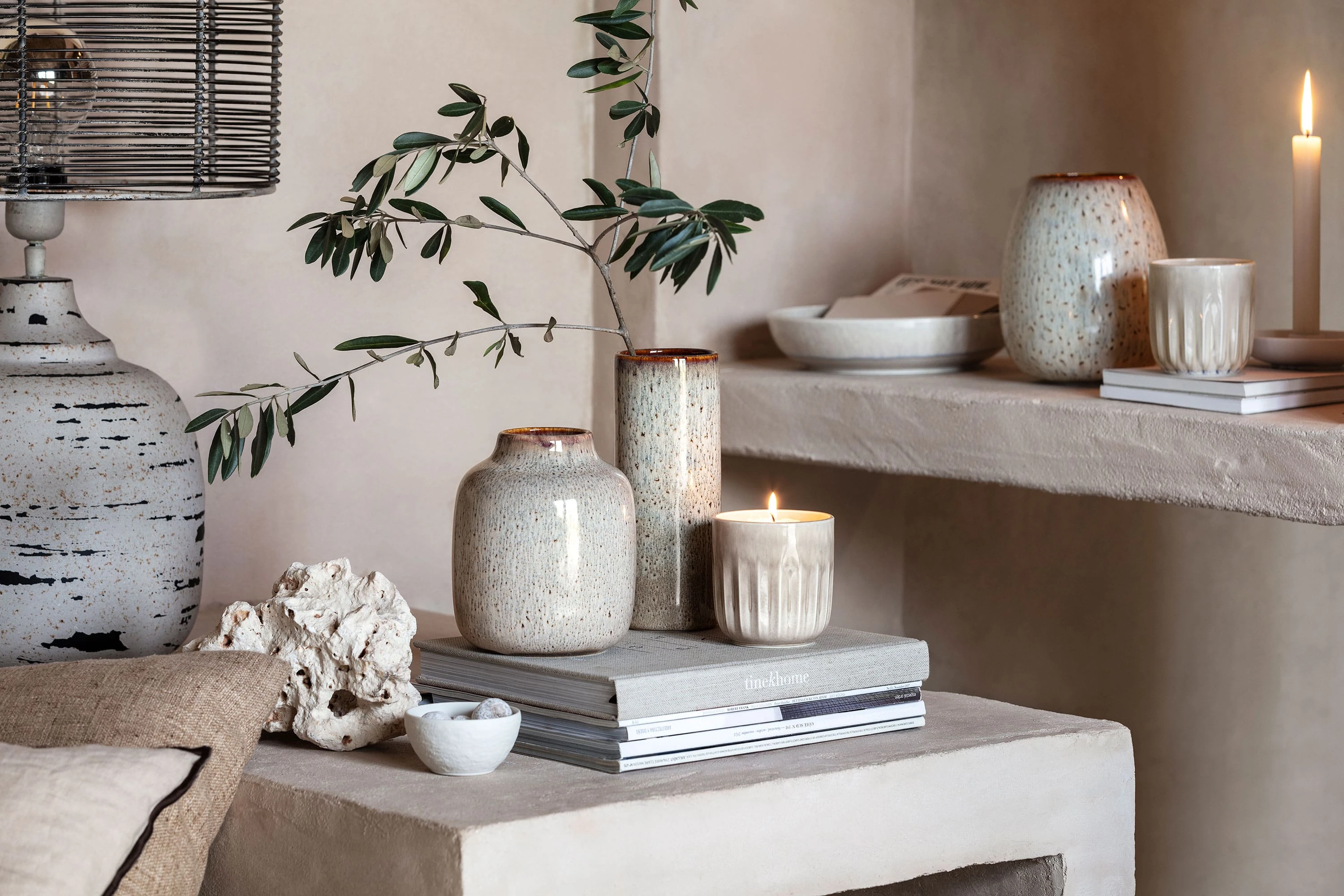 A living room with Perlemor scented candles, Lave vases and books on a shelf.