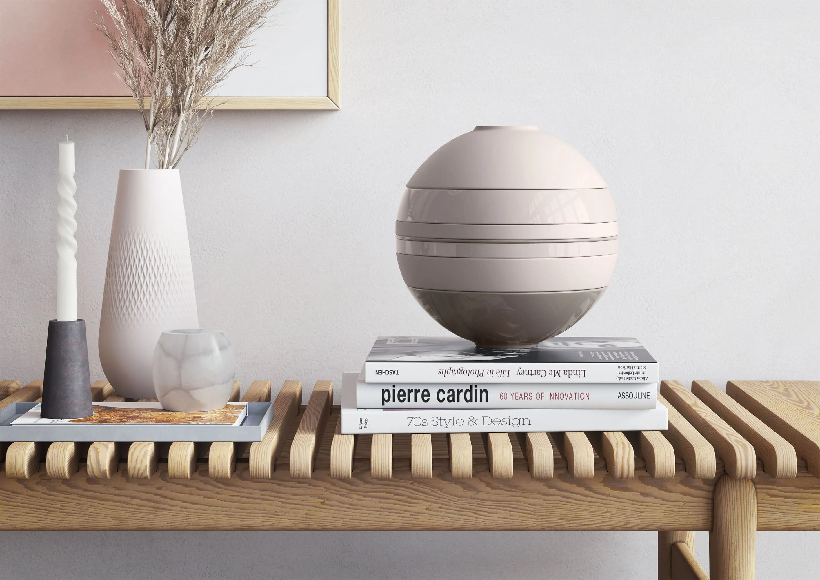 La Boule beige de Villeroy & Boch sur une table en bois à côté d’un vase et de livres.