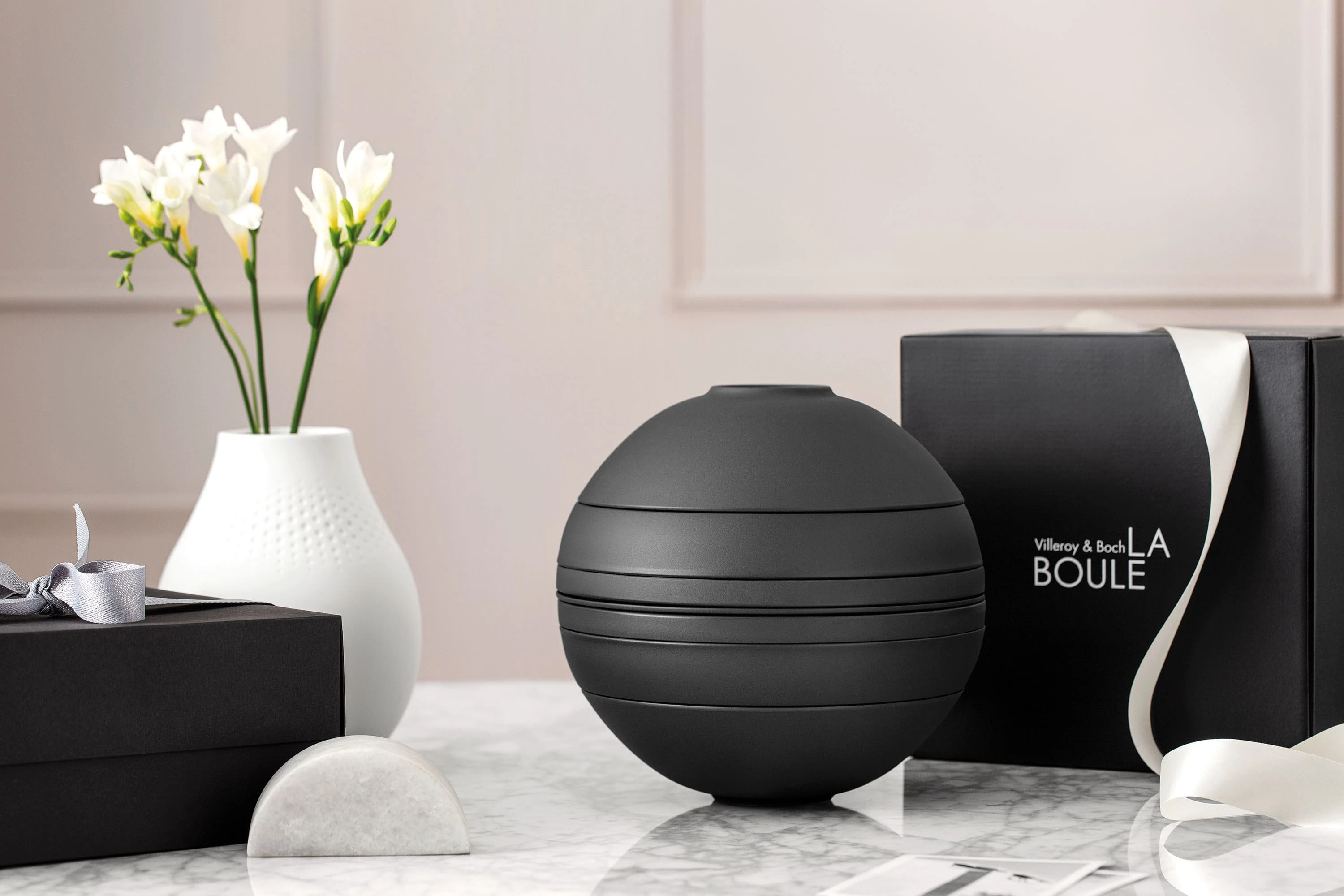 Un ensemble de vaisselle noir La Boule assemblé et posé une table accompagné d’un coffret cadeau noir.