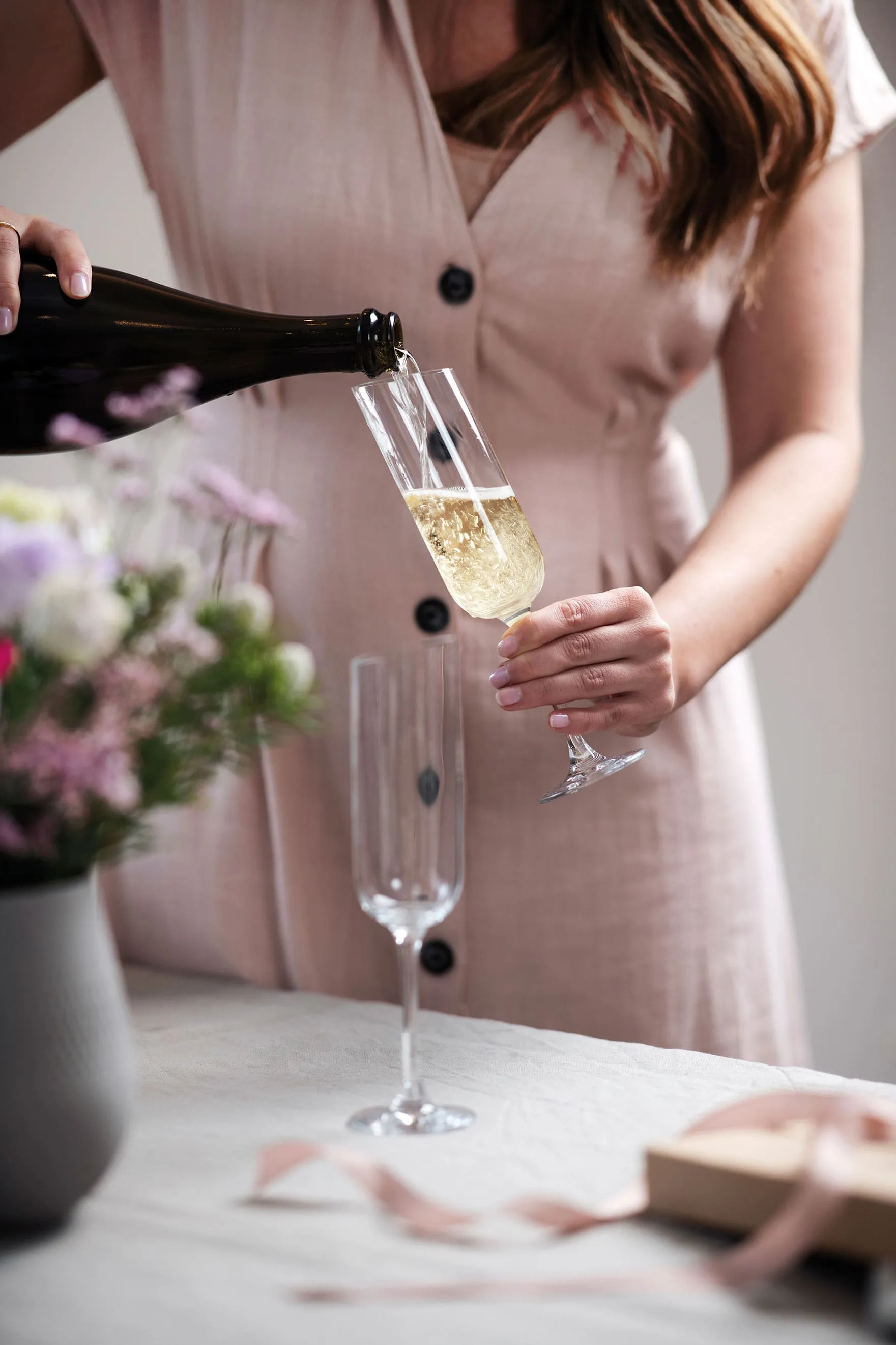 Une femme verse du champagne dans une flûte à champagne NewMoon de Villeroy & Boch.