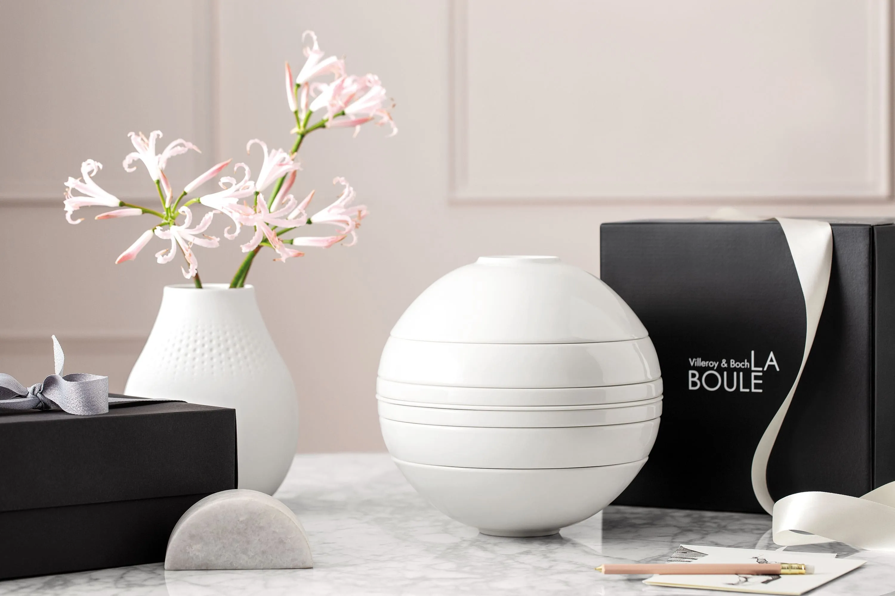 Un ensemble de vaisselle blanc La Boule assemblé et posé une table accompagné d’un coffret cadeau noir.