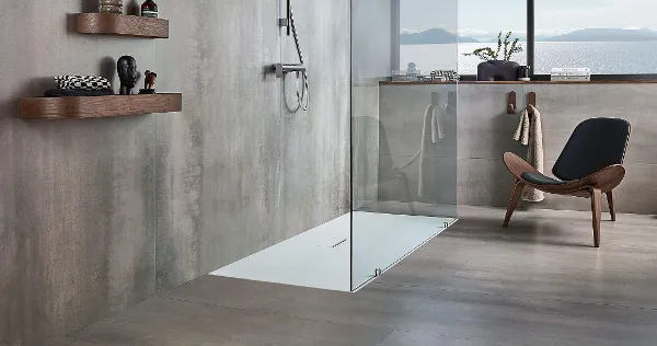 Une salle de bains grise moderne avec un receveur de douche Squaro Infinity et une chaise marron.