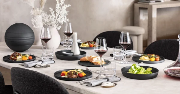 A dining table with a black La Boule being used for food as well as a fully assembled La Boule for decoration.