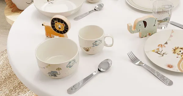 A table setting in the children's room with boho kids dinnerware, flatware and glasses in an animal theme in pastel colors.