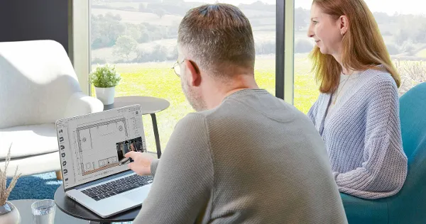 Espace de travail avec deux personnes Deux personnes sont assises devant un ordinateur portable. L'homme pointe l'écran.