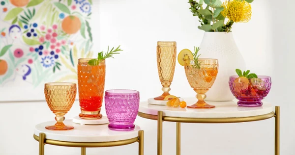 Colorful summer drinks in various Boston glasses on a chic serving table with a flower painting in the background.