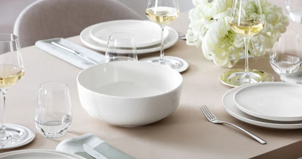 Large empty Villeroy & Boch Afina serving bowl on a laid table, with flowers in the background.