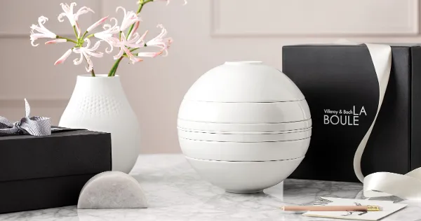 A white La Boule dinnerware set on a table with a black gift box behind it.
