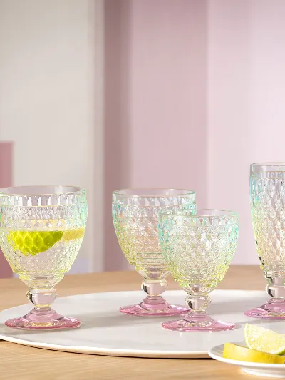 Un ensemble de six verres Villeroy & Boch Boston Pearl sur une table en bois avec des tranches de citron vert et de citron, un verre avec une paille et une tranche de citron.