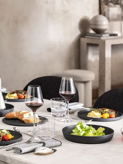 Een eettafel met een zwarte La Boule in gebruik met eten en een in elkaar gezette LaBoule als decoratie.