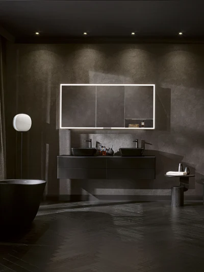 Svart baderom med frittstående badekar og dobbeltservant Dramatisk Artis helsvart baderom med frittstående badekar, dobbeltservant, opplyst speil og myk belysning for en dristig og luksuriøs atmosfære.