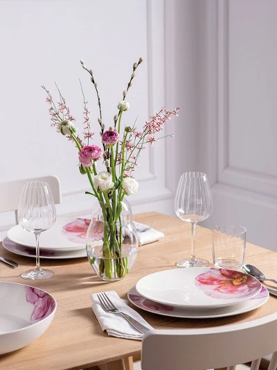 Une table de salle à manger moderne dressée pour quatre personnes avec une élégante vaisselle Rose Garden de Villeroy & Boch et un vase de fleurs de la collection Rose Garden.