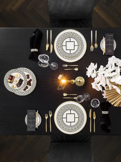 HOTSPOT: Luxurious dining table with elegant MetroChic crockery, cutlery and a flower arrangement on a dark wooden floor.