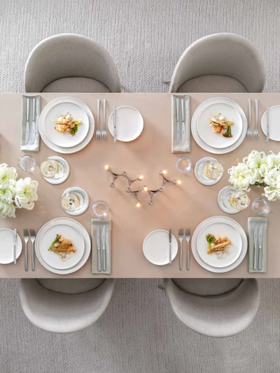 Afina crockery with Piemont cutlery on a beige dining table with warm candlelight Elegant dining table set for six people, with white Afina crockery, Piemont cutlery and warm candlelight.