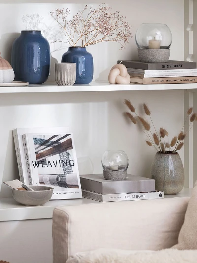 A living room with bookshelves and blue Lave vases from like. by Villeroy & Boch.