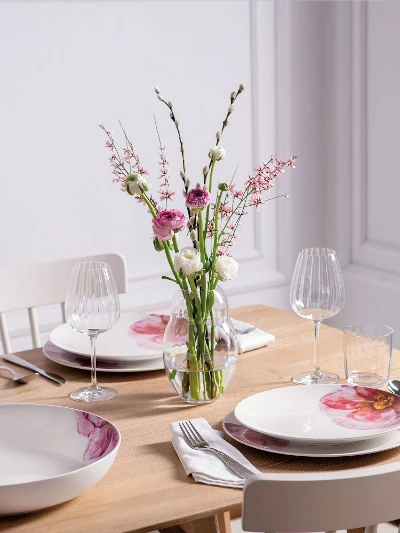 Une table de salle à manger moderne dressée pour quatre personnes avec une élégante vaisselle Rose Garden de Villeroy & Boch et un vase de fleurs de la collection Rose Garden.