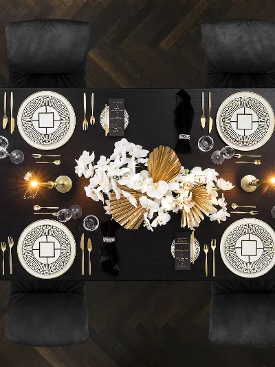 Luxe eettafel met elegant MetroChic servies, bestek en een bloemstuk op een donkere houten vloer.