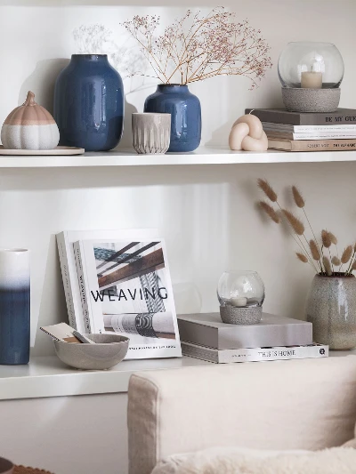 Een woonkamer met boekenplanken en blauwe Lave vazen van like. by Villeroy & Boch.