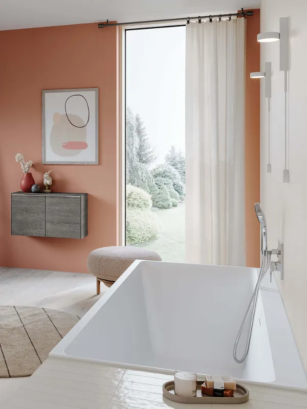 Une salle de bains moderne avec des murs orange et une baignoire Subway 3.0 blanche.