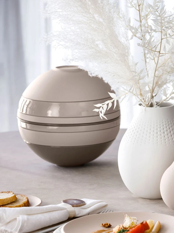 Una tavola apparecchiata con una La Boule beige e vasi Manufacture di Villeroy & Boch.