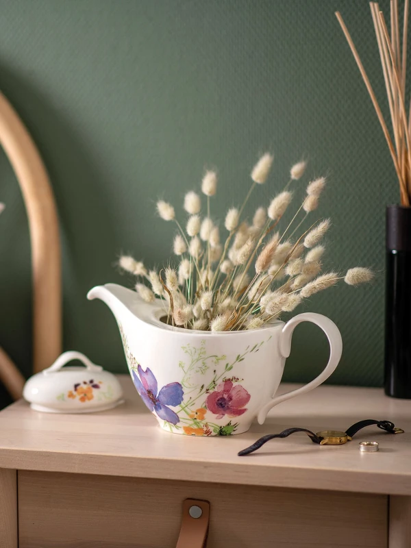 Une théière Mariefleur utilisée en guise de décoration avec des fleurs séchées sur une table de nuit.