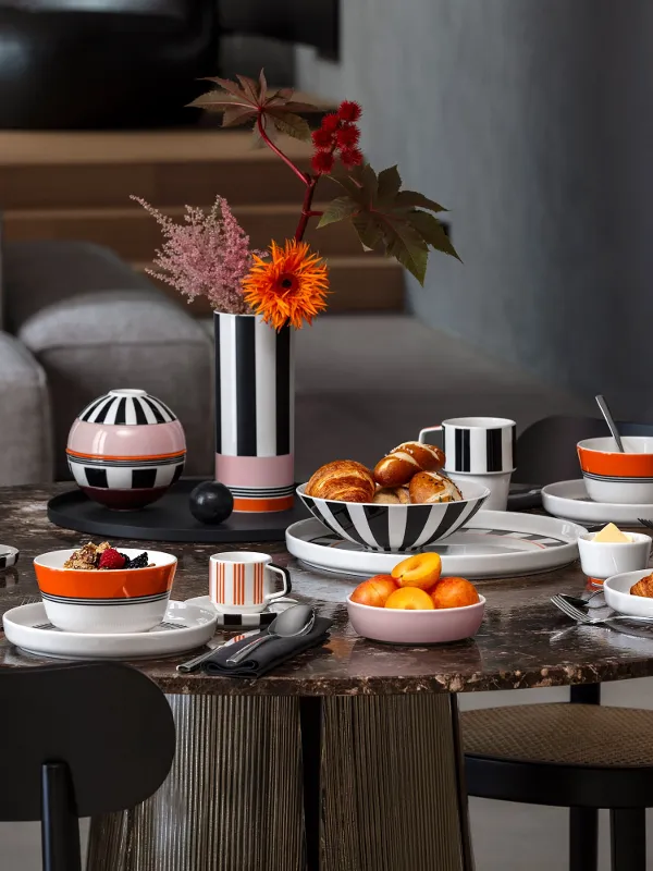 A round breakfast table set with croissants, fruit, coffee and black and white striped crockery from the Memphis collection by Villeroy & Boch.