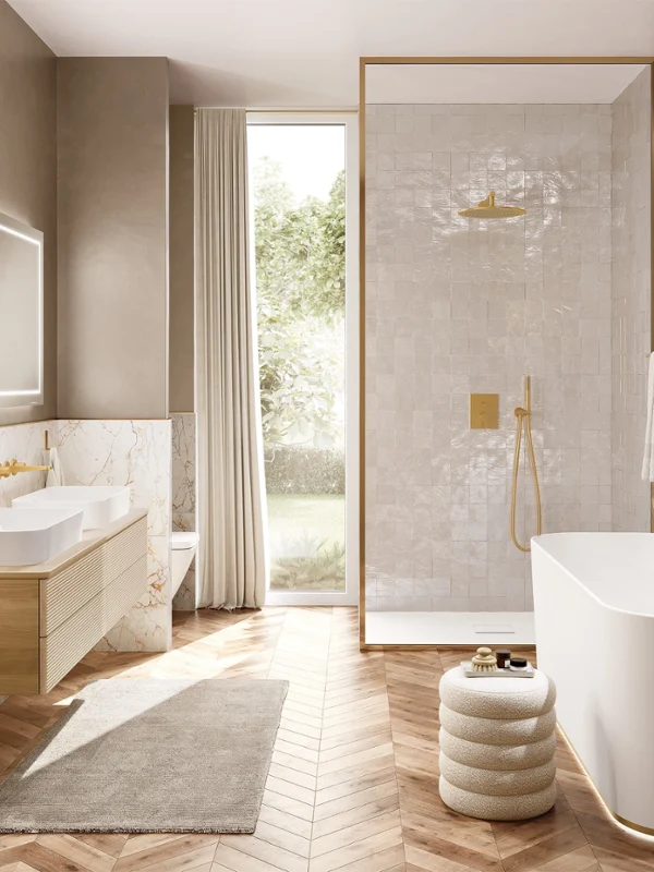 A bright bathroom with white sinks and light wooden bathroom furniture. All fittings are gold