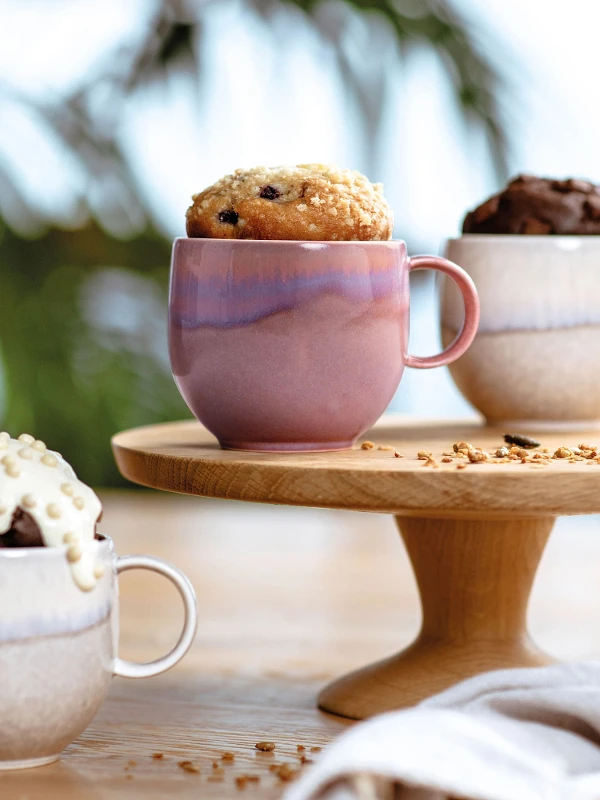 Three Perlemor mugs filled with mug cake on a wooden stand.