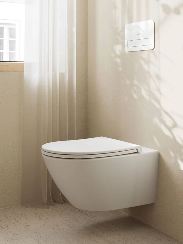 Badezimmer mit Badewanne im All Black-Stil Minimalistisches Badezimmer mit schwarzer Collaro Vorwand-Badewanne, dunklen Wänden, zwei runden Wandleuchten und einem grünen Handtuch. Schatten und eine kleine Pflanze verleihen der Szene Struktur.