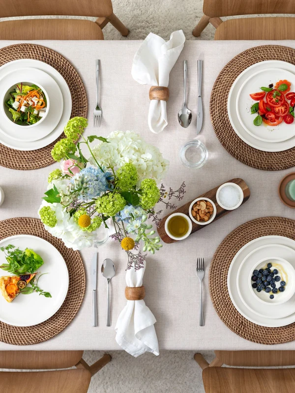 Draufsicht auf ein rustikales Tischgedeck für vier Personen mit Speisen auf Villeroy & Boch Artesano Original Porzellan – Speise- und Frühstücksteller, Schalen, Pastateller, Dip-Schalen, runde Servierschale, Antipastiteller, Salatbesteck und Piemont Besteck. Eine warme, einladende Szene für ungezwungene Mahlzeiten mit Familie oder Freunden.