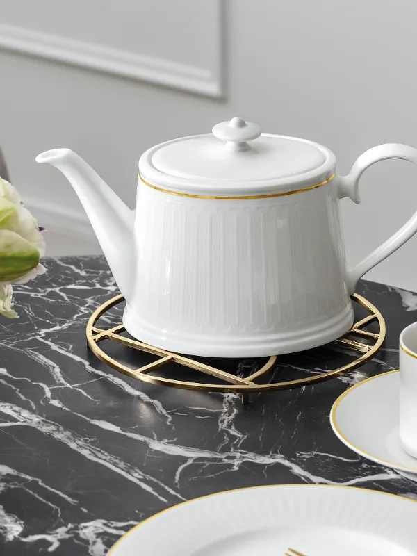 Elegante Teekanne von Chateau Septfontaines neben einer Steinvase von Manufacture auf einem stilvollen Marmortisch, der ein raffiniertes Dekor präsentiert
