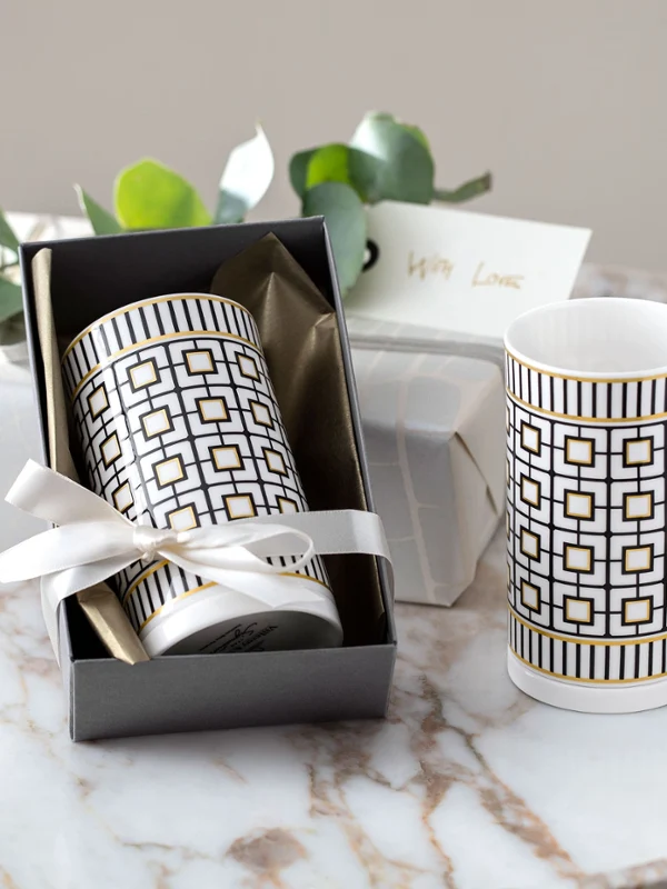 Due vasi MetroChic in una confezione regalo, accompagnati da candele e un biglietto su un tavolo di marmo.