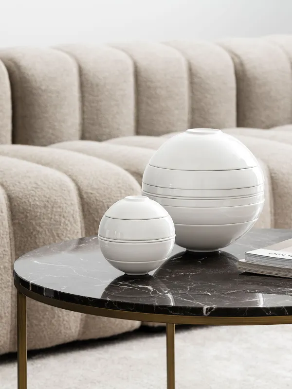 A modern living room with a gray, textured sofa and a black marble coffee table decorated with the La Boule in various sizes.