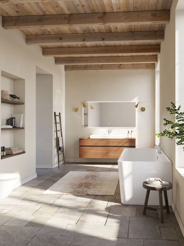 Une salle de bains spacieuse au design moderne avec une baignoire, des toilettes murales, un grand lavabo, un plafond en bois et une grande fenêtre. Des étagères avec des livres et de la décoration ainsi qu’une plante complètent l’aménagement.