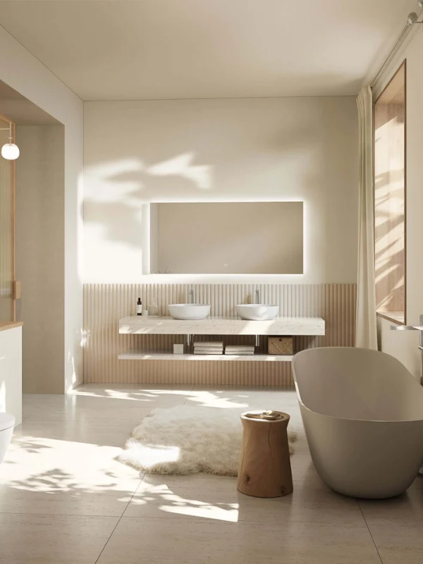 A modern bathroom with two round Artis washbasins on a marble countertop, a mirror, toiletries, folded towels and a storage basket underneath.