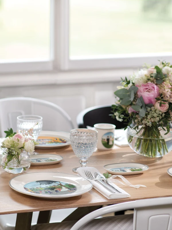 Een romantisch gedekte tafel met Design Naif servies en NewMoon bestek, plus bloemen en kaarsen.