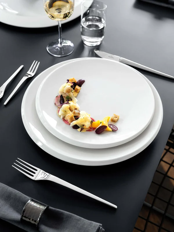 Elegant gedeckter Esstisch mit NewMoon Tellern und Weingläsern.