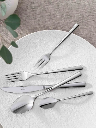 Elegant table decor with modern Piemont flatware and decorative green on a neutral table cloth.