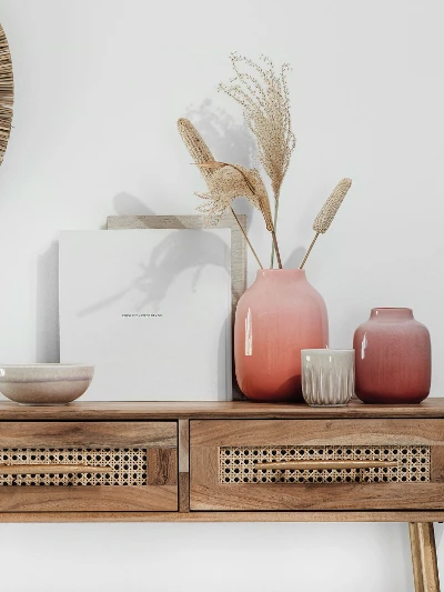 A wooden console table with Perlemor vases and a round mirror.