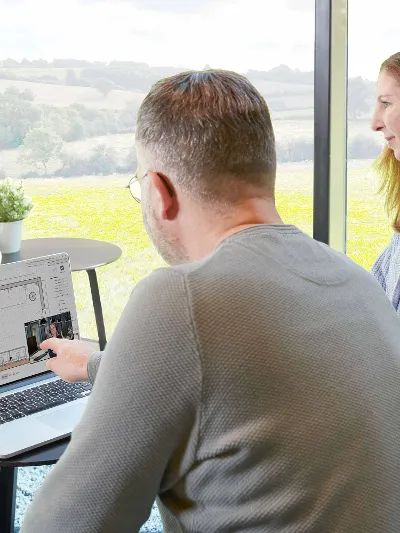 Espace de travail avec deux personnes Deux personnes sont assises devant un ordinateur portable. L'homme pointe l'écran.