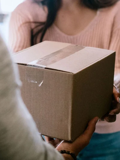 Handing over a box A person hands a box to another person in a doorway.