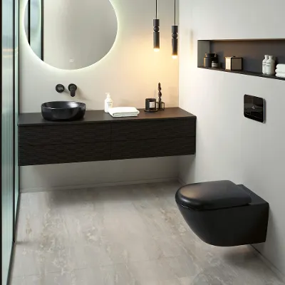 Une salle de bains avec des toilettes noires ainsi qu’un lavabo de la collection Antao dans une pièce moderne au look noir et blanc.