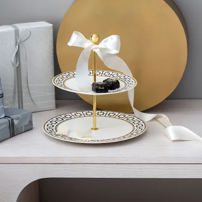  A MetroChic tiered cake stand with pastries surrounded by gift boxes and a bow on a wooden table.