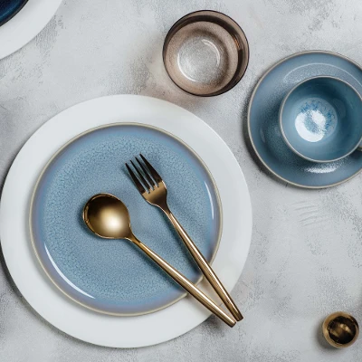 Elegant table decor with blue Crafted dinnerware and white Royal dinnerware, golden MetroChic flatware and a matching napkin.