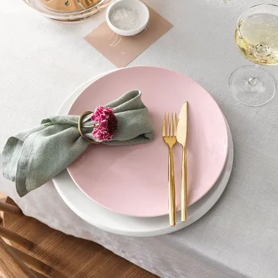 Une table dressée avec une assiette de couleur rose Rose Garden, une assiette blanche NewMoon et des couverts de table dorés MetroChic.